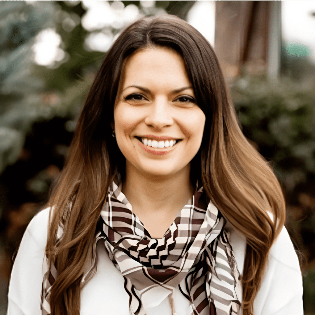 Smiling woman wearing a patterned scarf outdoors.