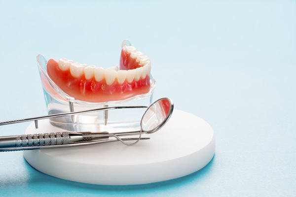 Dentures with dental tools on blue background.