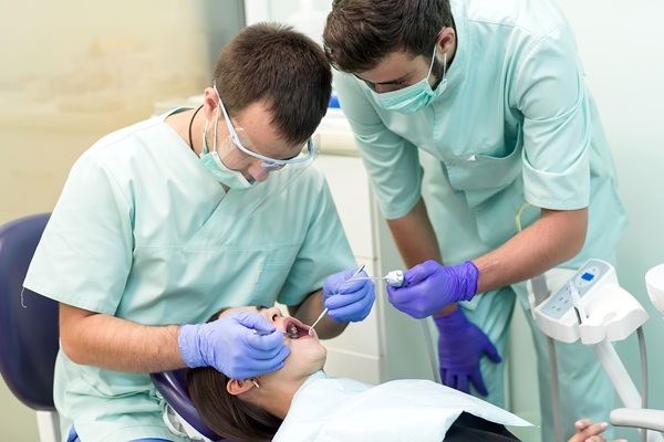 Dentists performing dental procedure on patient.