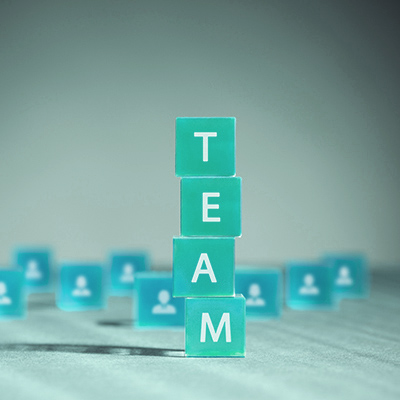 Stacked blocks spelling TEAM with blurred blocks in the background.